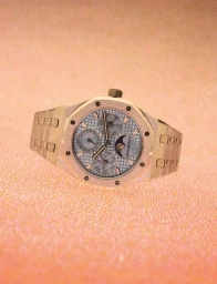 Gold luxury wristwatch with patterned grey dial set against a textured warm-toned paper background