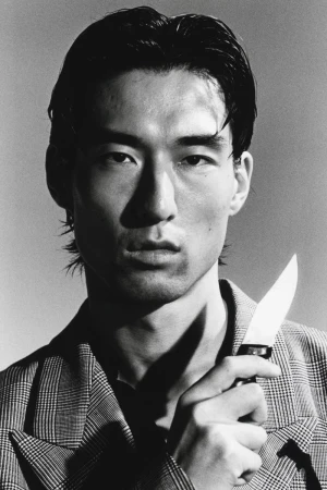 Portrait of an Asian man wearing a plaid blazer holding a knife in a dramatic black and white editorial shoot for HERO Magazine.