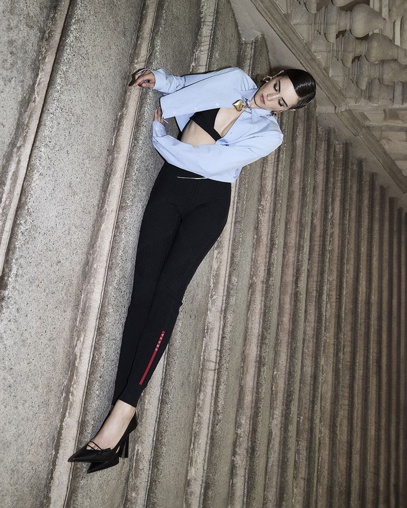 Model Kim Schell posed against ornate stone architectural stairs wearing a light blue cropped shirt and black trousers for Amica Magazine