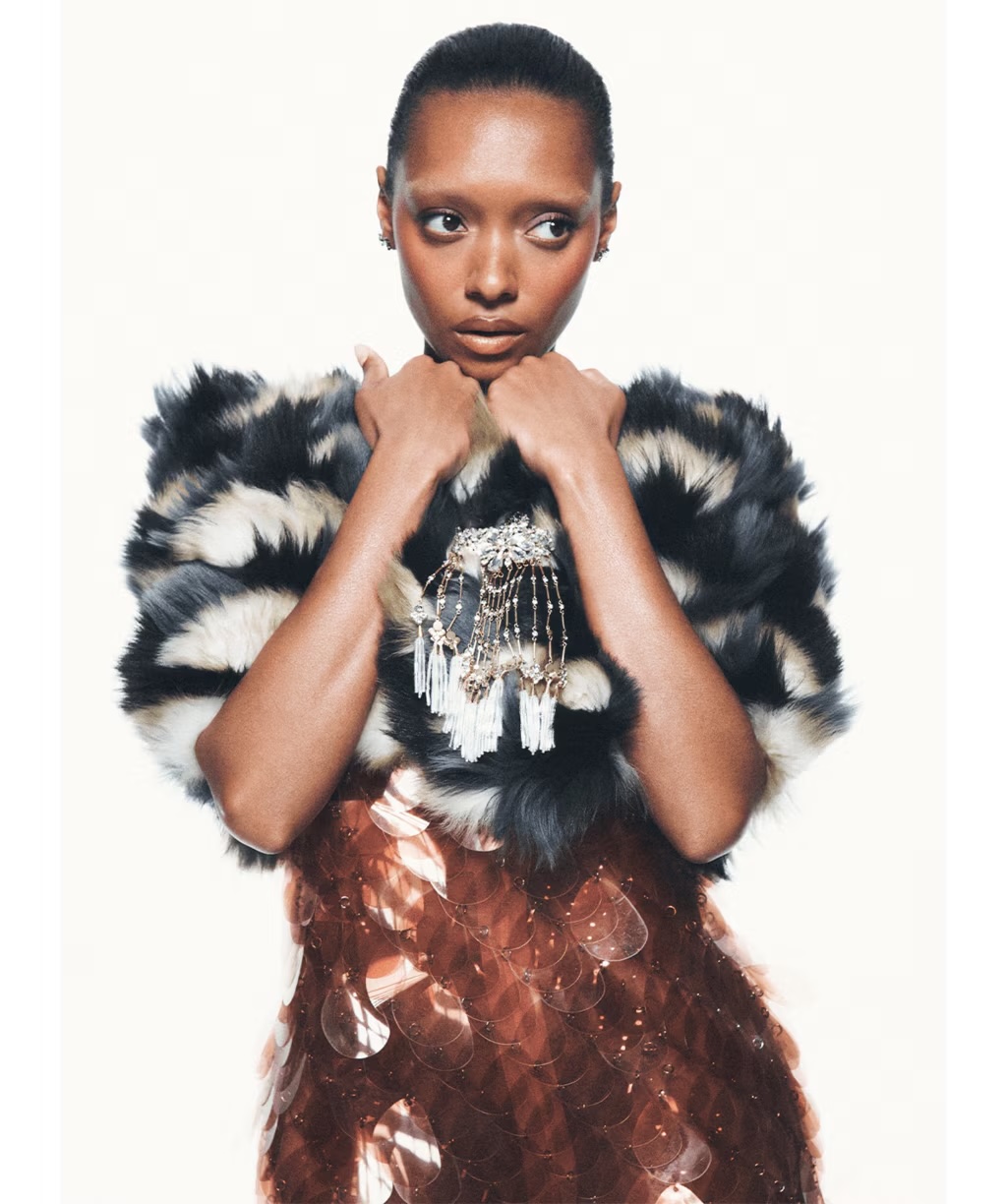 Sophie Wilde in a textured black and white fur stole and bronze sequined dress against a bright white background.