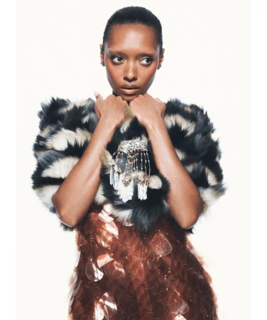 Sophie Wilde in a textured black and white fur stole and bronze sequined dress against a bright white background.