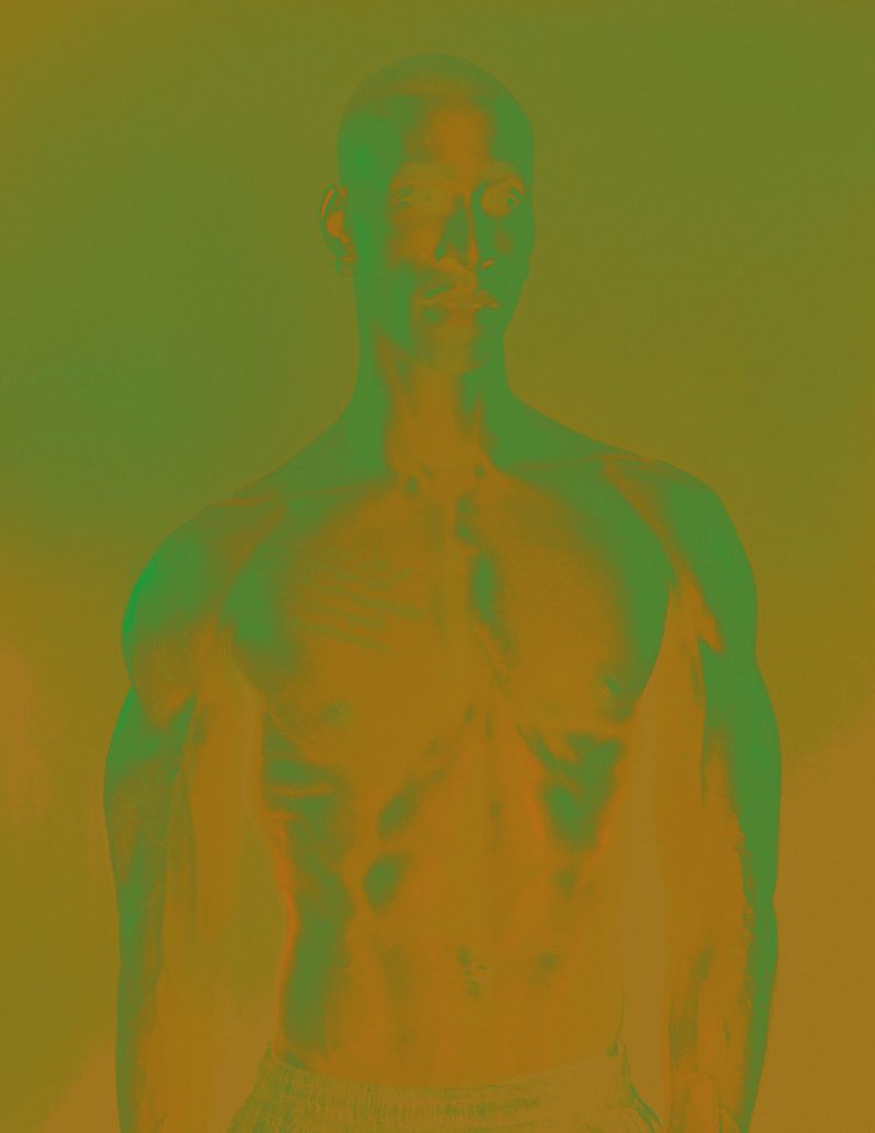 Portrait of a shirtless man with arms down against an olive green and golden background with a color grade effect