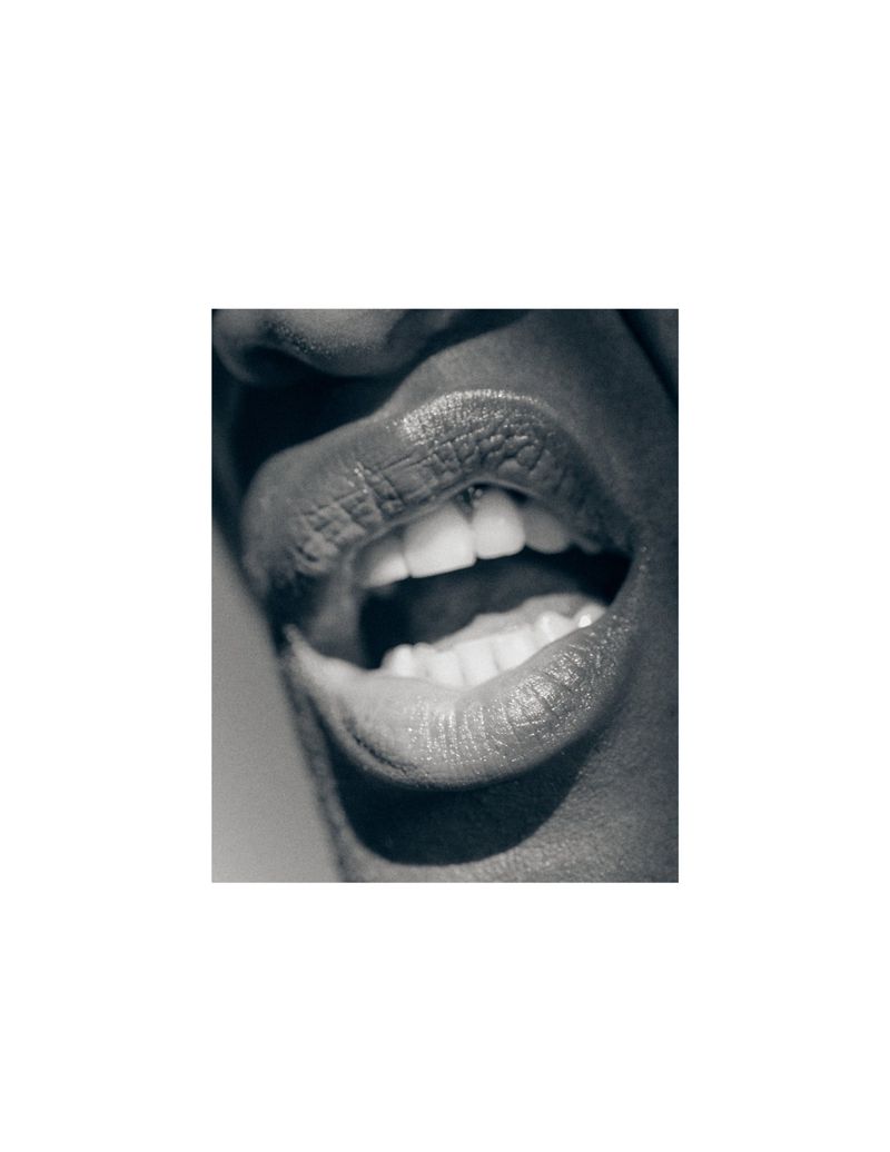 Close-up macro shot of a person's open mouth revealing white teeth against a minimal white border background.