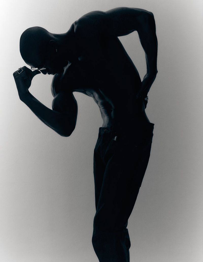 Silhouette of a muscular shirtless man posing against a bright white background for Fucking Young