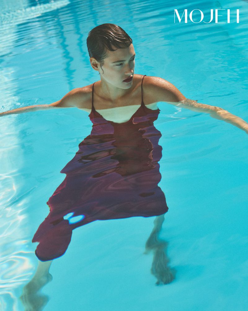 Model standing in a swimming pool wearing a dark slip dress, photographed for Mojeh Magazine
