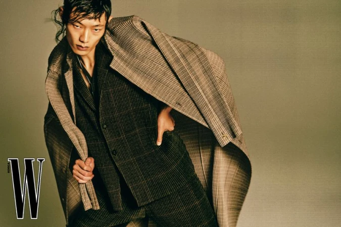 Asian male model wearing a patterned plaid suit and coat in a studio setting for W Korea magazine editorial.