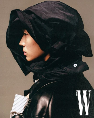 Profile portrait of a male model wearing an oversized black hooded garment and dark jacket for W Korea, photographed by Mok Jung Wook.