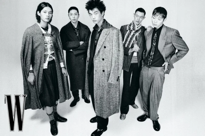 Monochrome fashion editorial image of five Asian male models in tailored coats and patterned knitwear posing against a white studio background.
