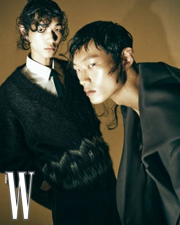 Two male models with styled wet hair wearing dark tailored garments in a fashion editorial for W Korea.