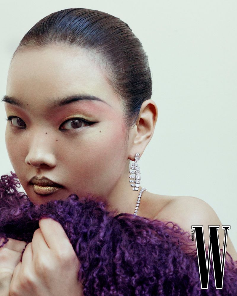 Close-up portrait of model Bomi Youn with pink eyeshadow, metallic gold lipstick, and a textured purple garment for W Korea.