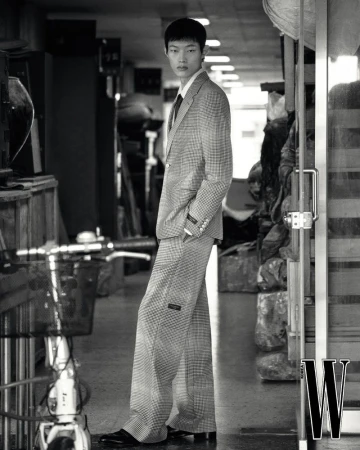 Model Hoyong Kim in a patterned suit standing inside a shop corridor, shot by photographer Park Jongha for W Korea.