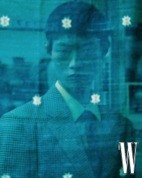 Model Hoyong Kim wearing a patterned suit behind a blue glass overlay for W Korea photographed by Park Jongha.
