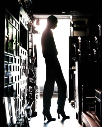 A silhouette of a model standing in high heels inside an antique shop against a bright window backdrop for W Korea