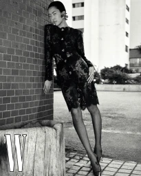 Model in black lace dress leaning against a brick wall for W Korea editorial