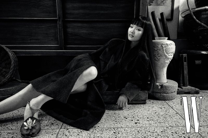 Model with long dark hair lying on a tiled floor in an antique market setting for W Korea magazine.
