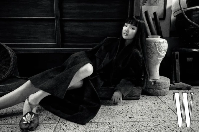 Model with long dark hair lying on a tiled floor in an antique market setting for W Korea magazine.