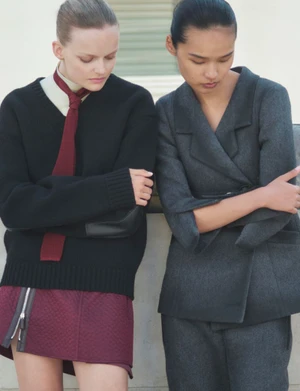 Two female models posing outdoors wearing dark tailored clothing for a fashion editorial story.