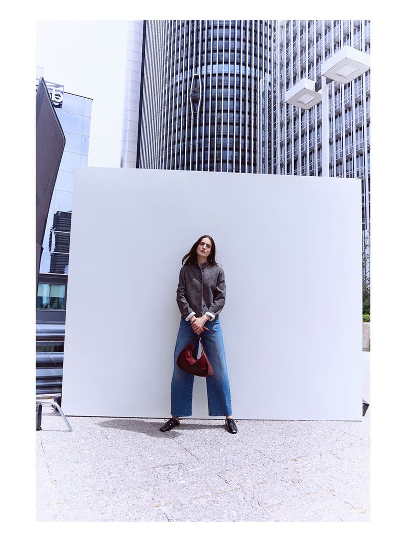 Model Blanca Padilla standing in front of a white panel with modern skyscrapers in the background during the Latouche F/W 2026 campaign.