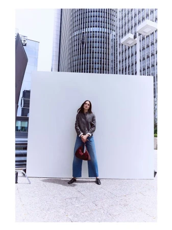 Model Blanca Padilla standing in front of a white panel with modern skyscrapers in the background during the Latouche F/W 2026 campaign.