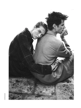 Black and white editorial fashion portrait of two models embracing outdoors on a stone surface