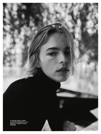 Black and white editorial portrait of a model with short tousled hair wearing a dark turtleneck outdoors.