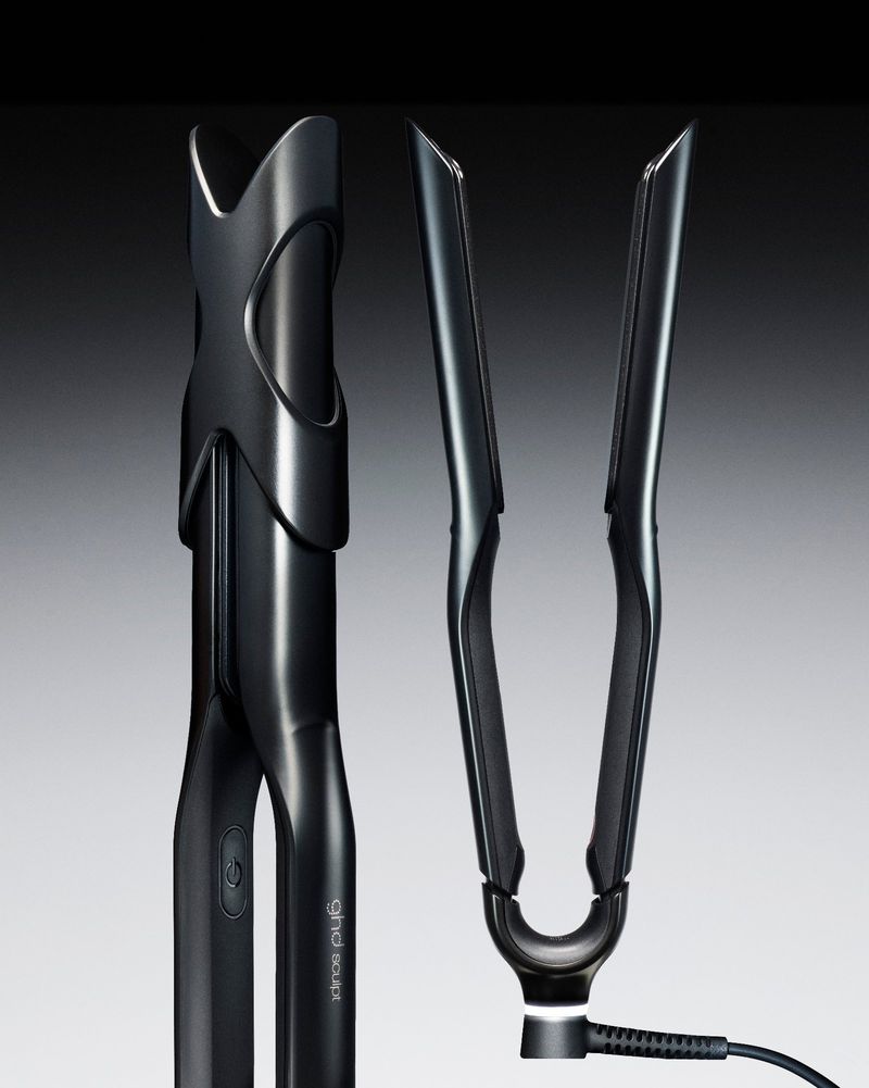 Close-up advertising product shot of a sleek black hair styling tool shown in closed and open positions on a gradient background