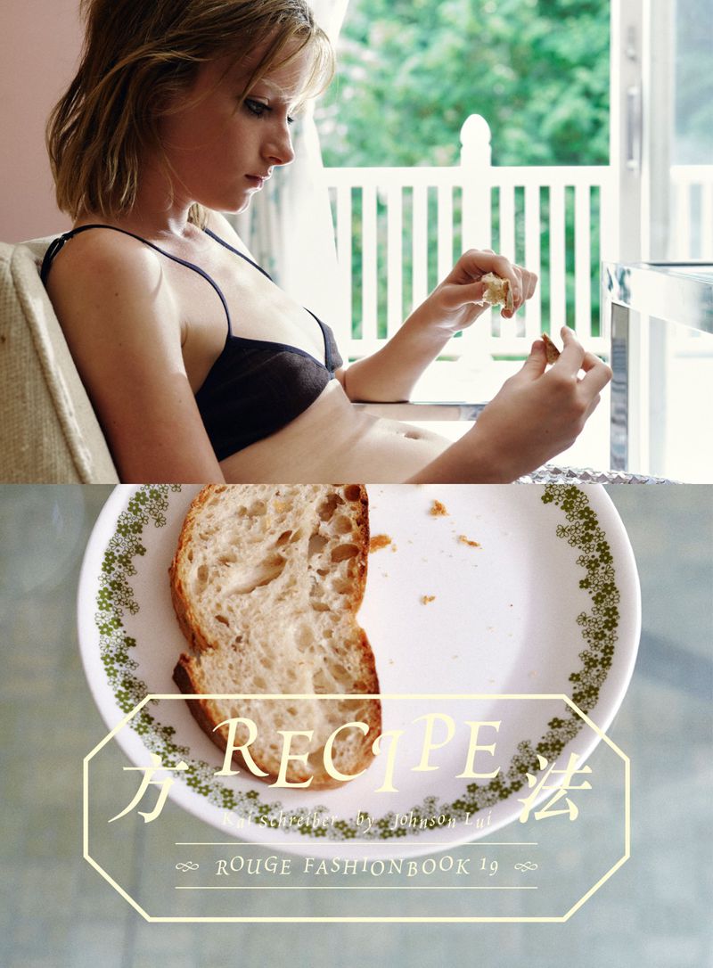 Model seated indoors holding pieces of bread, with a plate of sliced bread in the foreground bearing editorial text.