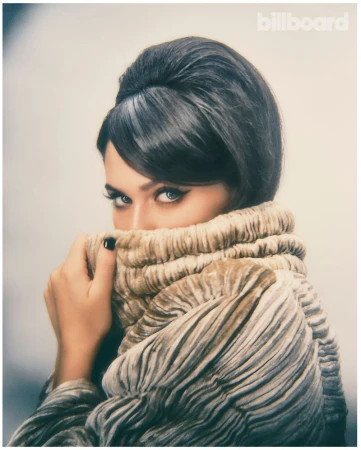 Sienna Spiro holding a gathered velvet collar up to her face with winged eyeliner and retro bouffant hair