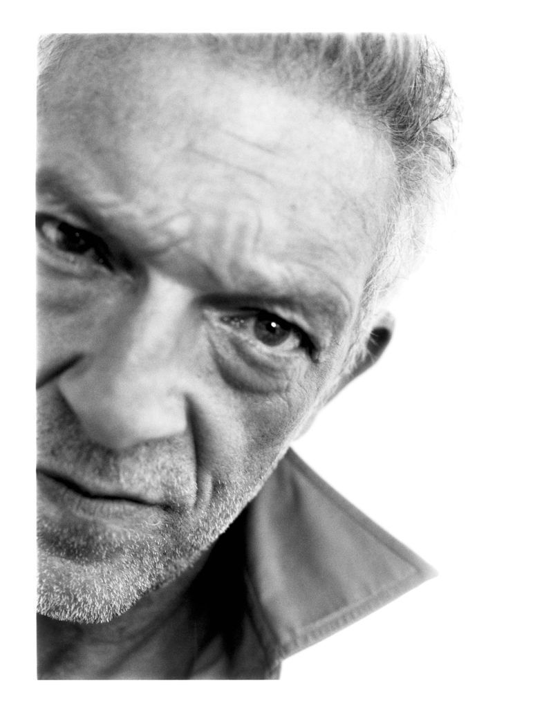 Close-up black and white portrait of Vincent Cassel looking intently at the camera against a white background