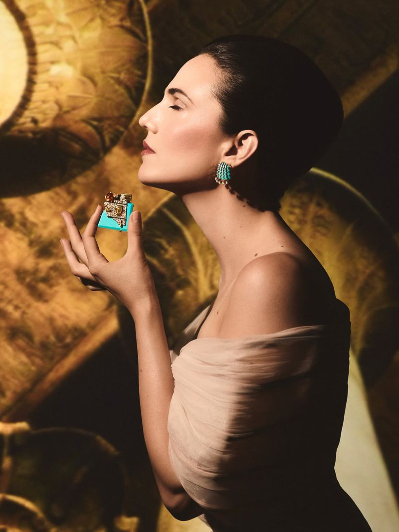 Profile portrait of a woman wearing statement earrings holding a small decorated object for Vogue Arabia