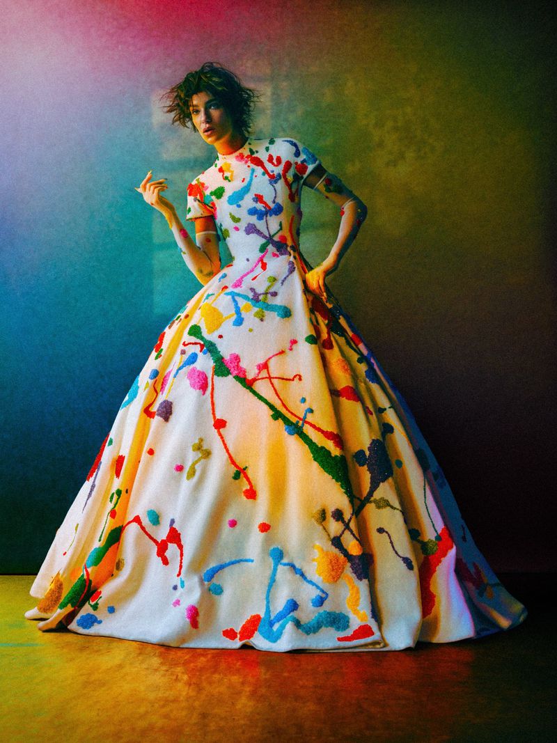 Model Lisa Louis Fratani wearing a white gown painted with vibrant colorful splatters in an editorial fashion photograph.