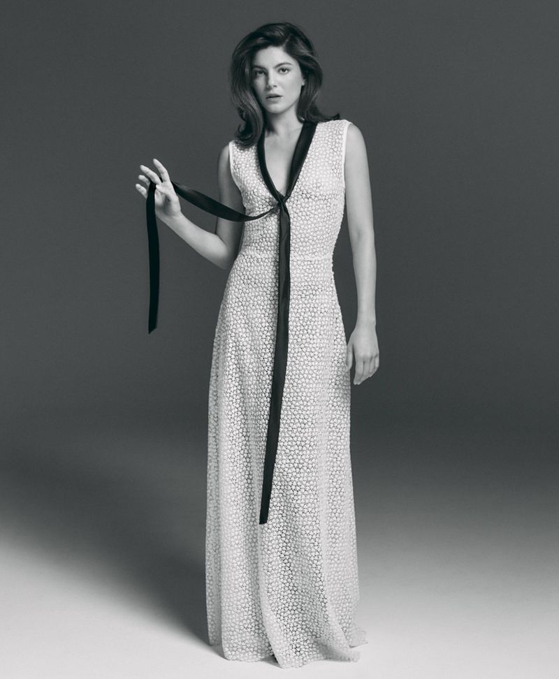 Monica Barbaro wearing a textured white gown with a black ribbon tie against a grey studio backdrop for Telegraph Luxury.