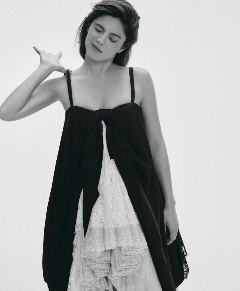 Monica Barbaro wearing a layered black and white dress against a plain white studio background for Telegraph Luxury.