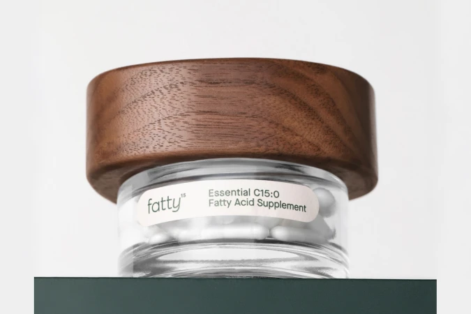 Glass supplement jar with a rich wooden lid and white label against a light background