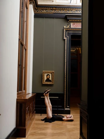 Model lying on parquet floor with legs raised in museum gallery for Le Monde Beryl campaign