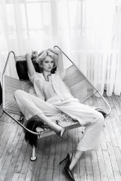 Model Lex Peckham reclining on a metal-frame lounge chair in an editorial portrait for Flaunt Magazine.