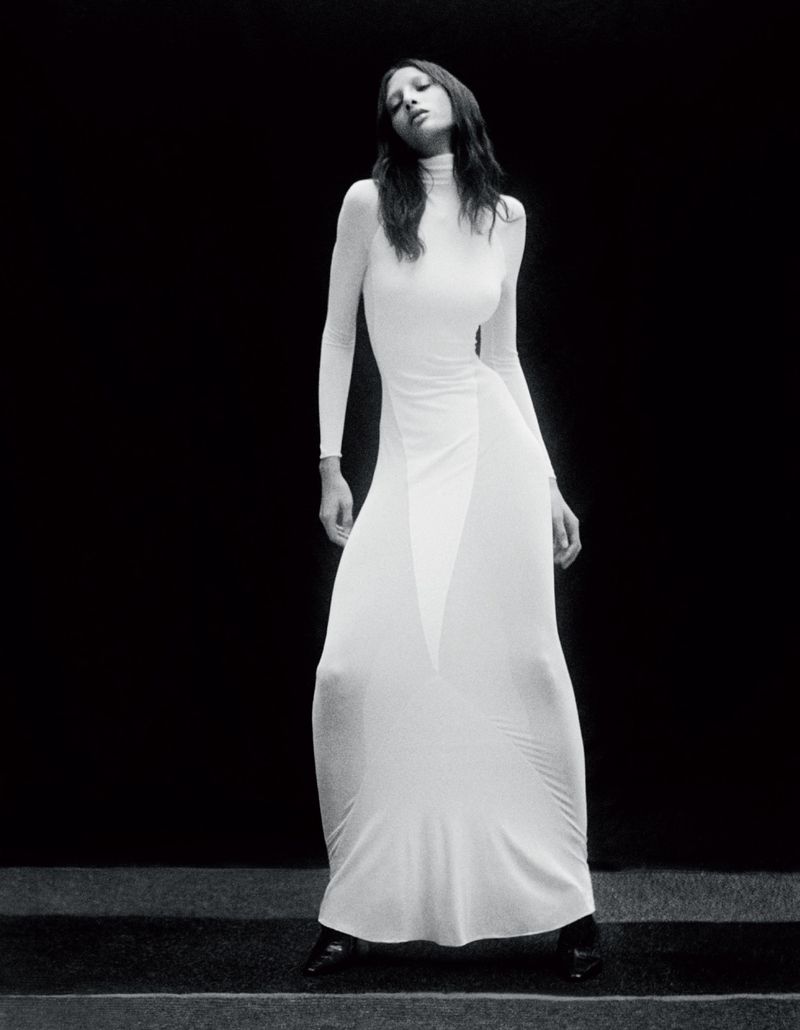 Model Yasmin Wijnaldum wearing a long white turtleneck dress against a dark background for Vogue Adria