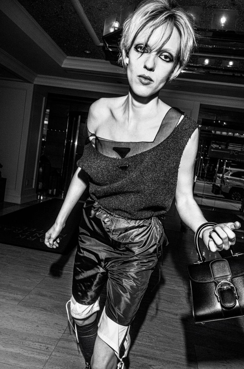 Model with dark eye makeup holding a black handbag in an interior setting for Crash Magazine