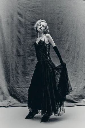 Model Sasha Krivko wearing a black slip dress and opera gloves posing against a textured dark backdrop for Crash Magazine.