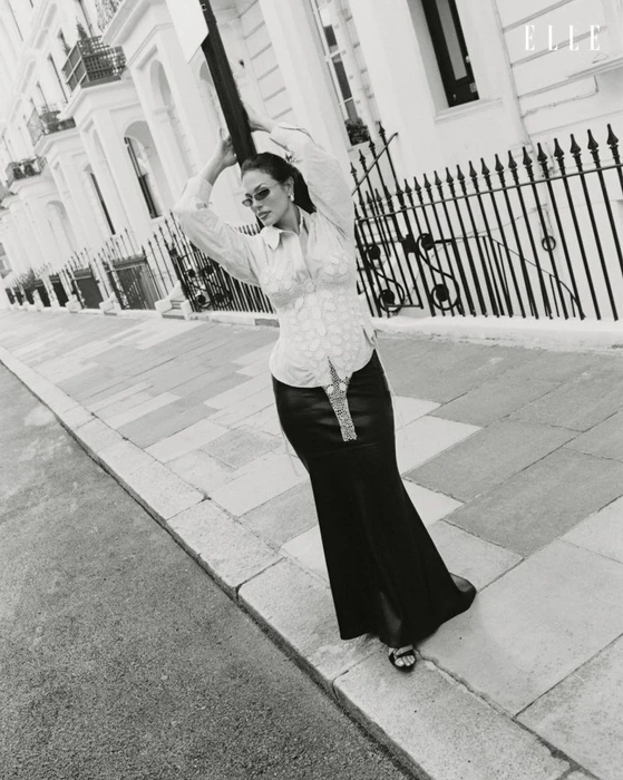 Ashley Graham posing on a city street in a patterned shirt and long dark skirt for Elle Netherlands editorial photography.