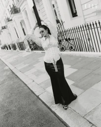 Ashley Graham posing on a city street in a patterned shirt and long dark skirt for Elle Netherlands editorial photography.