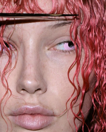 Close-up portrait of model Meredith Duxbury with wet pink curly hair and scissors cutting her bangs