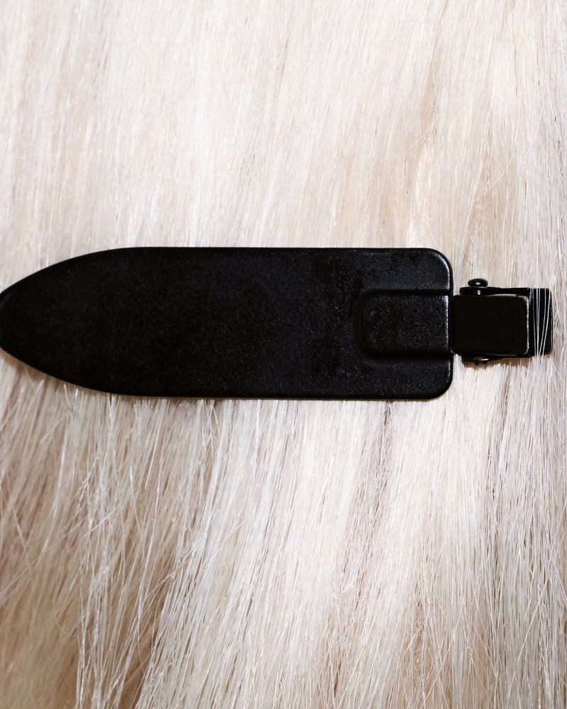 Close-up of a black hair clip fastened securely into long, platinum blonde hair.
