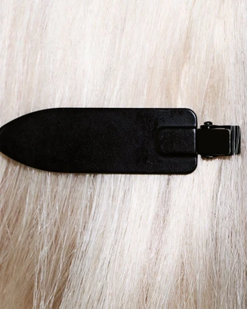 Close-up of a black hair clip fastened securely into long, platinum blonde hair.