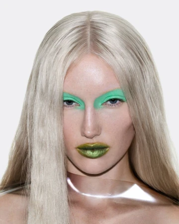 Close-up portrait of model Meredith Duxbury with long pale blonde hair, bright green eyeshadow, and metallic green lips.