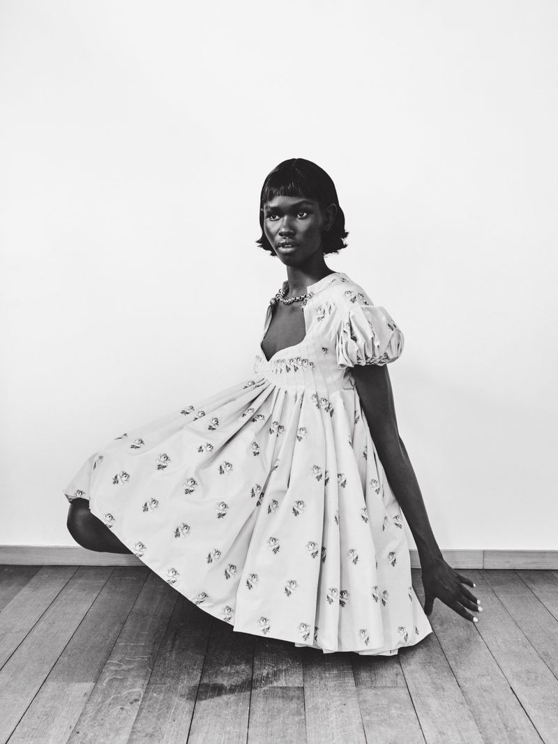 Model in a patterned puff-sleeve dress squatting in a white room with wooden floors for In Harmony 72 Magazine editorial
