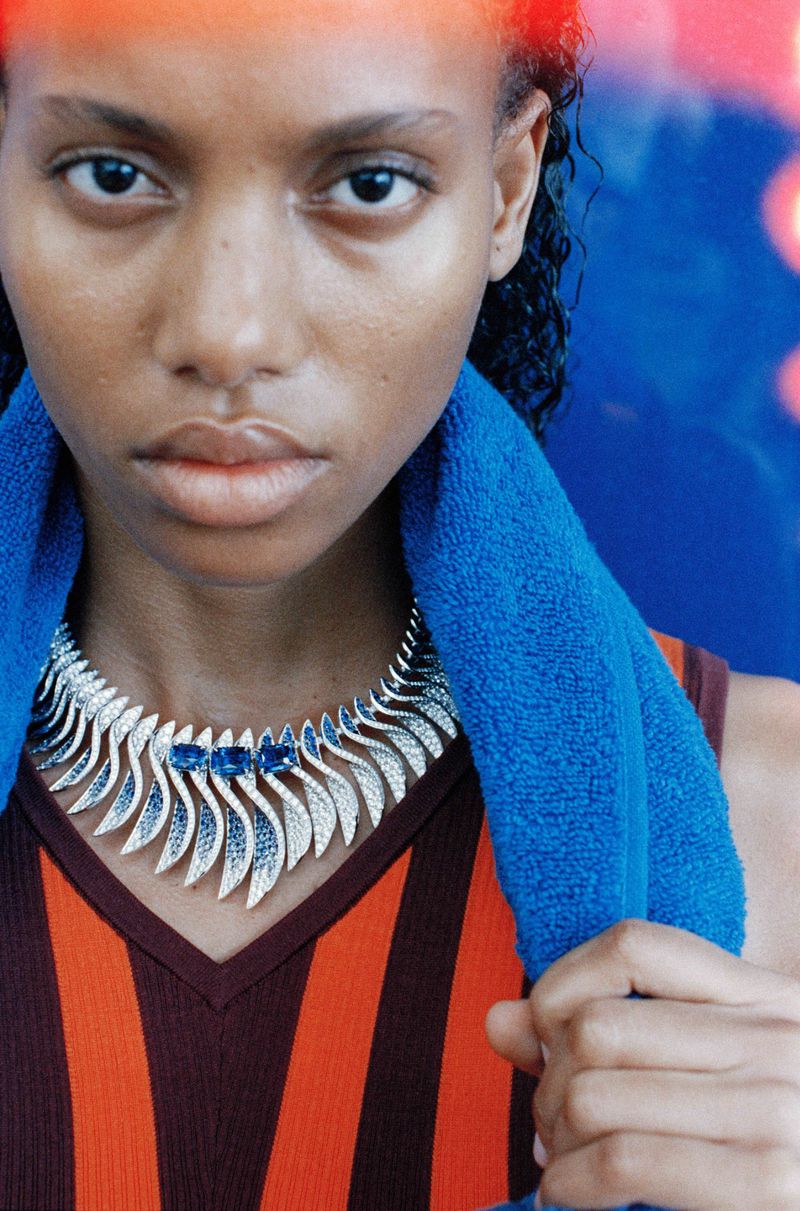 Close-up portrait of a woman wearing a statement diamond necklace and a bright blue towel draped over her shoulders