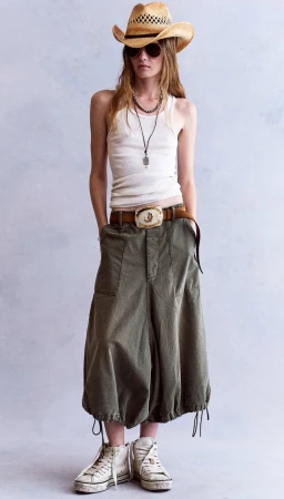 Model wearing a straw cowboy hat, white tank top, and olive utility pants against a plain grey backdrop
