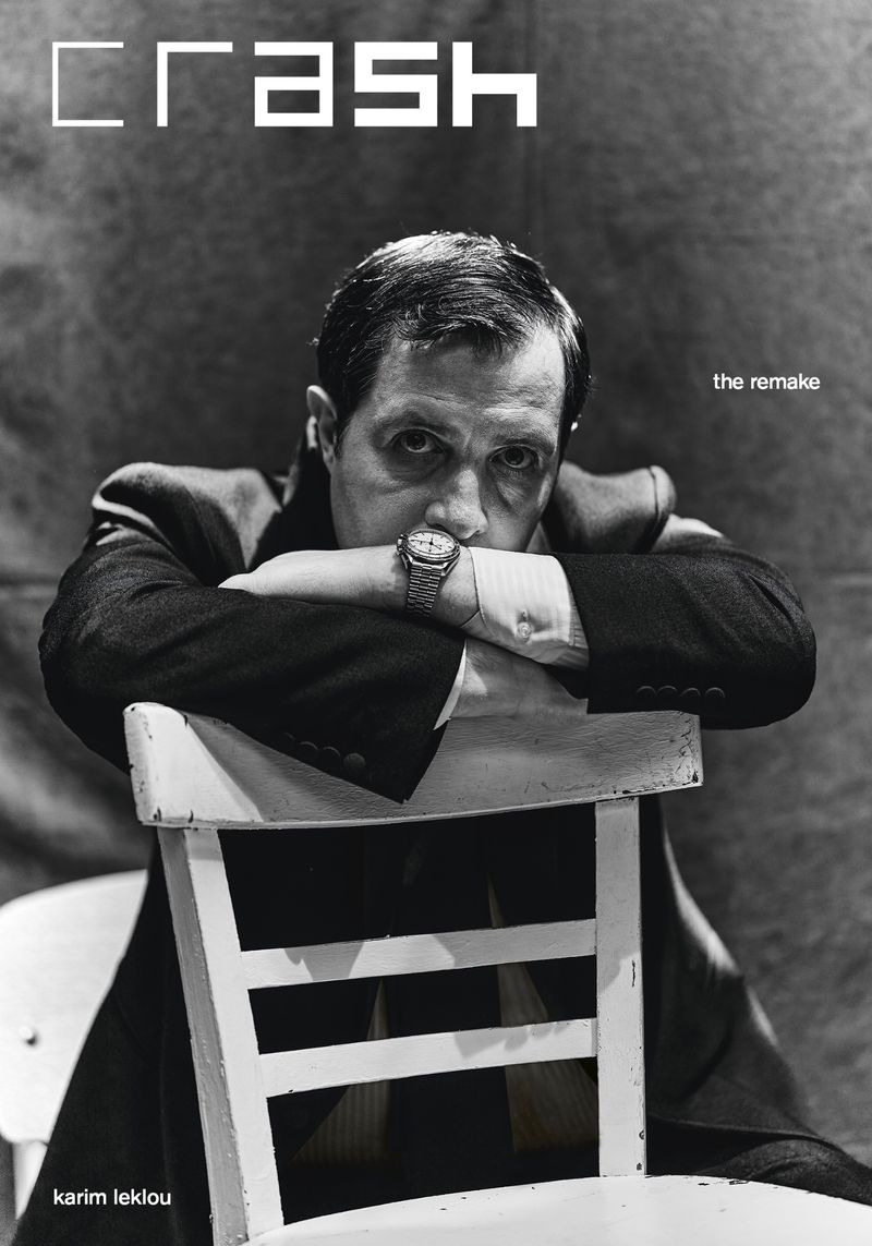 Monochrome portrait of Karim Leklou resting arms on the back of a white wooden chair for Crash Magazine