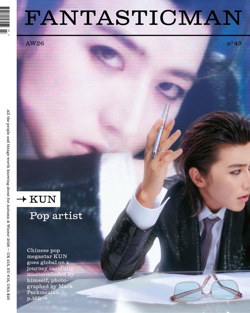 Magazine cover featuring Chinese pop star KUN wearing a dark suit and tie, holding a silver pen against a large screen background